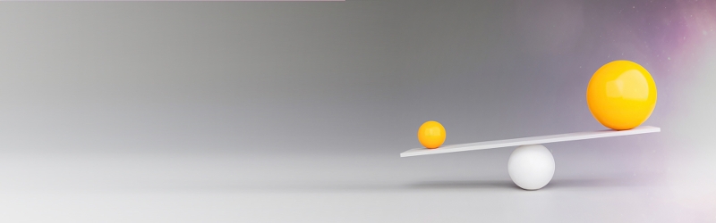 Image of weighing scales with two yellow spheres of different sizes on a grey background