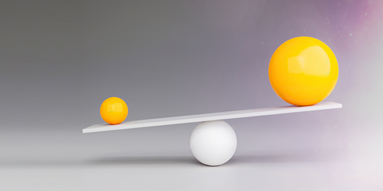 Image of weighing scales with two yellow spheres of different sizes on a grey background