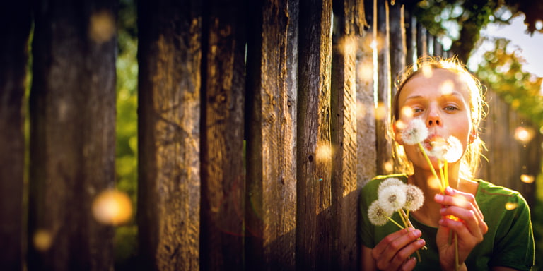 Minor investment account image of a young person blowing on dandy line flowers