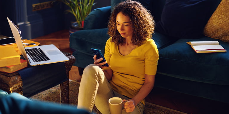 Tailored investment image of a smiling person on their phone in a living room