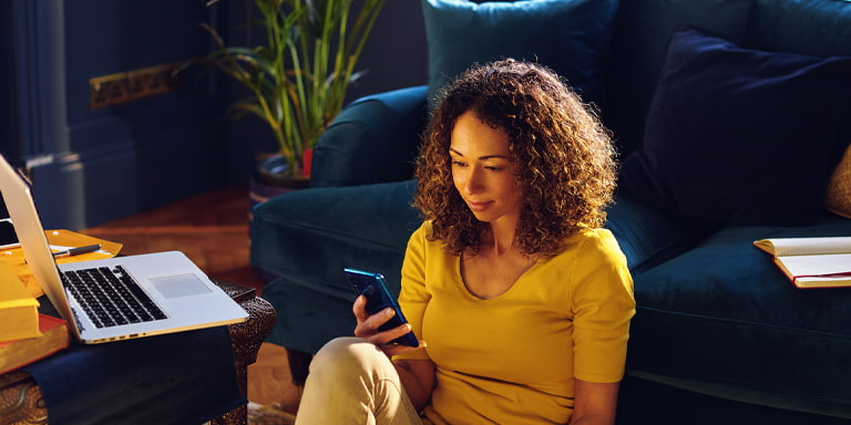 Tailored investment image of a smiling person on their phone in a living room